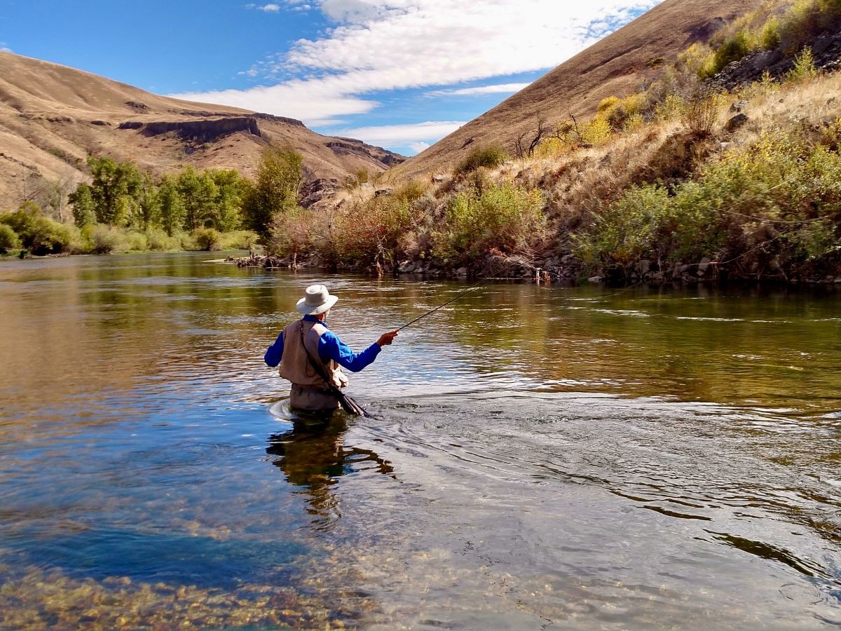 An angler with a delicate trout fly fishing outfit out in pursuit of wild trout in beautiful mountain strewn river surroundings.